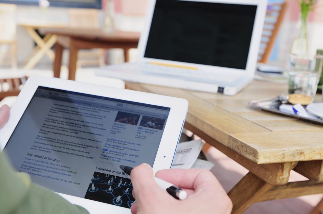 Person on iPad with laptop in front of them