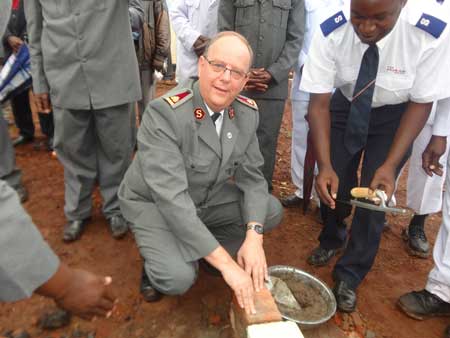 The General lays foundation stone of the Kakamega Central Corps in Kakamega Division, as the Corps Sergent Major looks on.