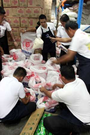 Colonel Wayne Maxwell, Lt. Colonel Alex Genabe Secretary for Program, and Major Reynaldo Magat at the SM warehouse in Manila with employees preparing 7 tons of food for dispatch to Tacloban