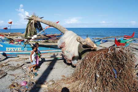 Children play on a beach near Tacloban, surrounded by beached fishing boats and uprooted trees photo by Major Dean Pallant