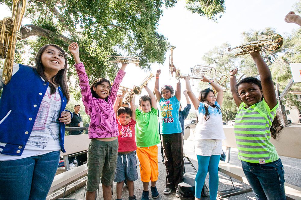 children smiling with hands in air outside