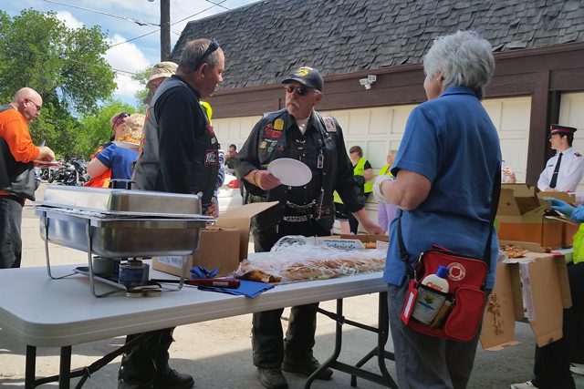 Volunteer Rosalind Weldele serves and talks with two Patriot Guard Escort Riders.