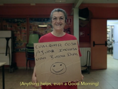 Homeless woman smiling with cardboard sign