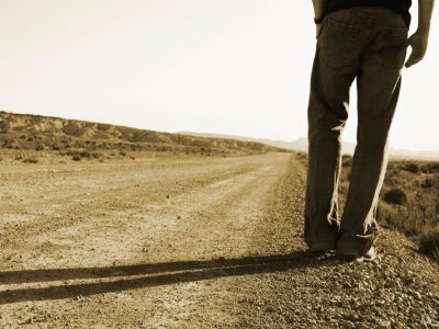 person standing on side of dirt road