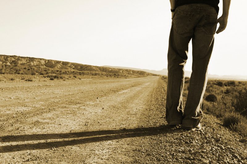 person standing on side of dirt road