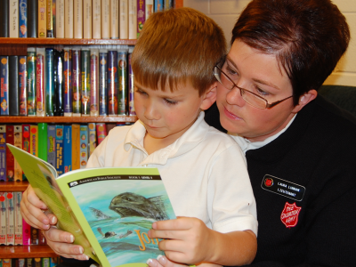 Salvationist reading with child on lap