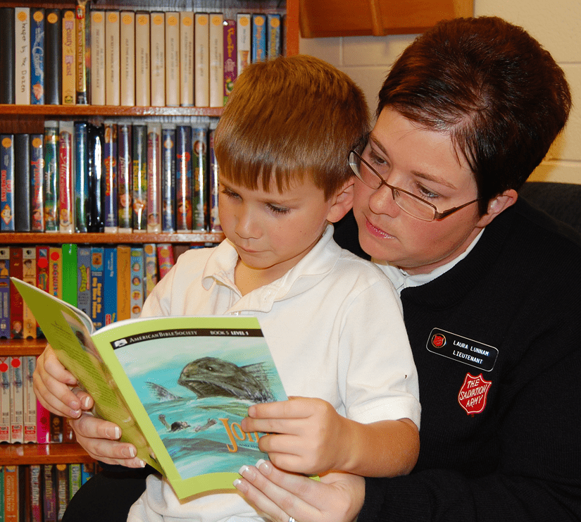 Salvationist reading with child on lap