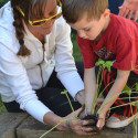 Woman helping child with plant
