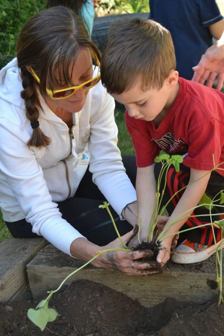 Woman helping child with plant