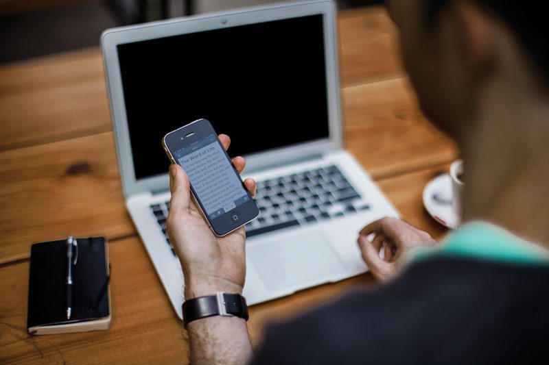 Person holding phone while on laptop