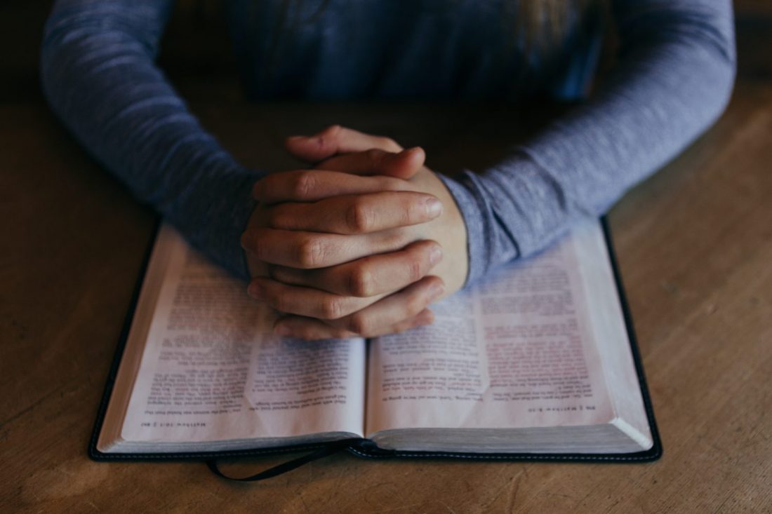 Hands folded over Bible