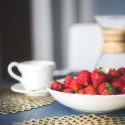 Bowl of strawberries next to coffee cup