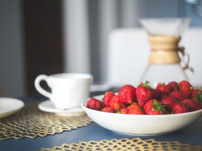 Bowl of strawberries next to coffee cup