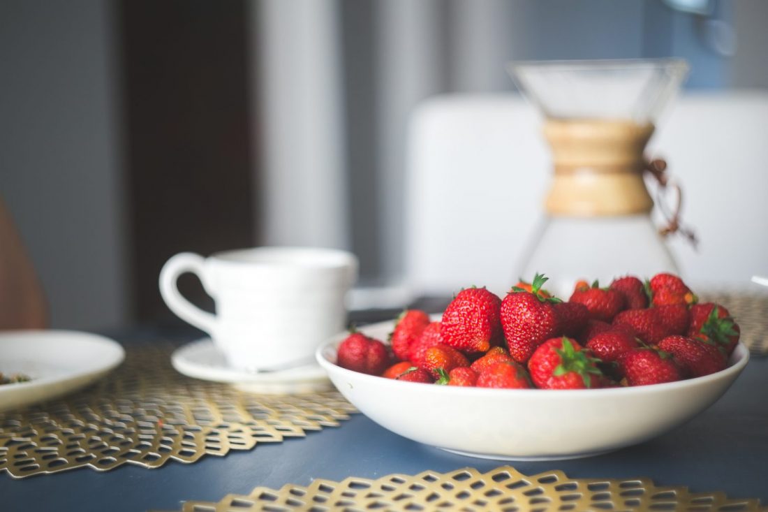 Bowl of strawberries next to coffee cup