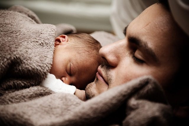 Man with baby sleeping on chest
