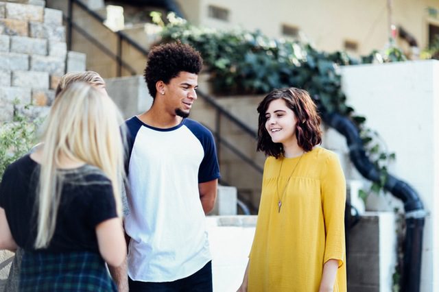 Two young women standing with young man