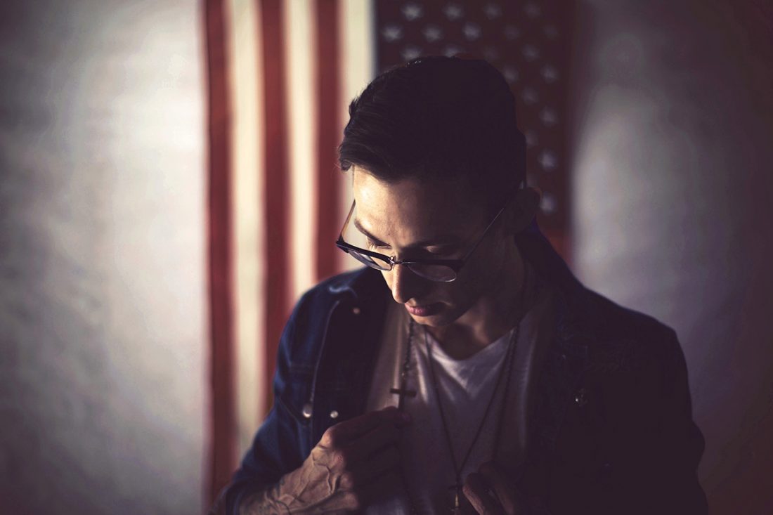 Man wearing cross necklace in front of American flag