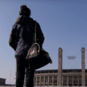 Person with gym bag standing outside Olympic building