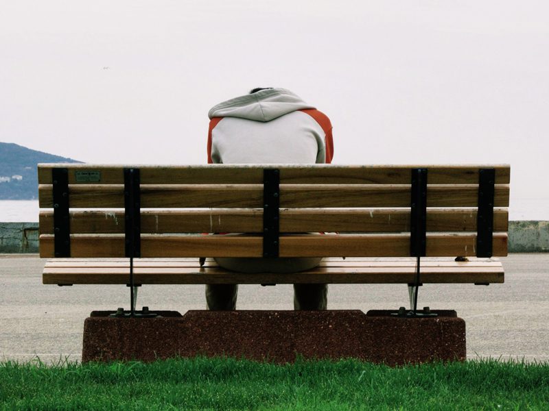 Person sitting on bench with head down