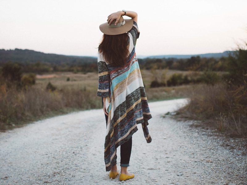 Woman holding hat outside on road