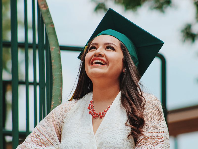 young woman in graduation cap smiling outside