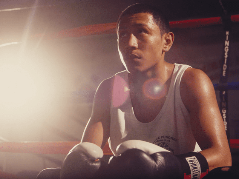 younger boxer looking focused sitting in ring