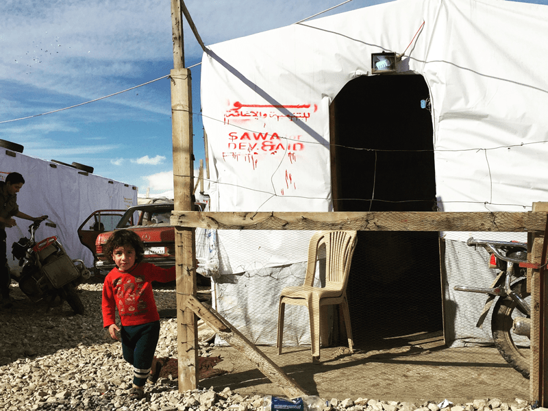 Child in front of tented house