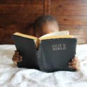 child reading bible on bed
