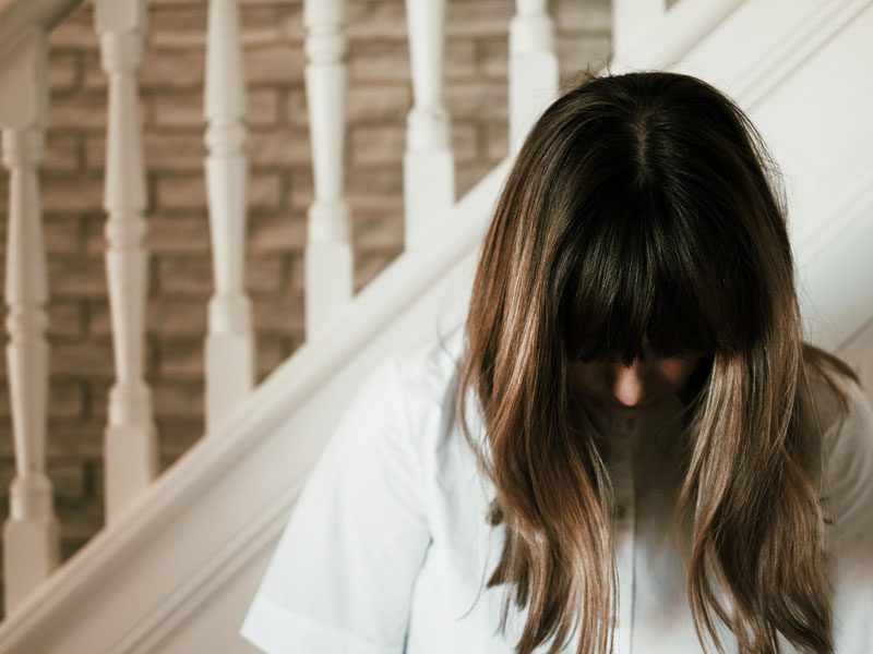 Woman in front of stairs looking down