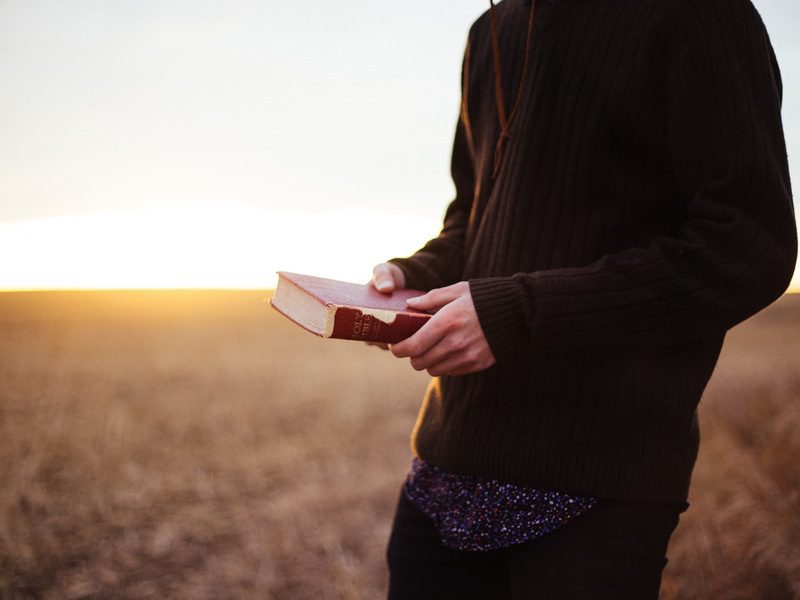 person holding Bible outside