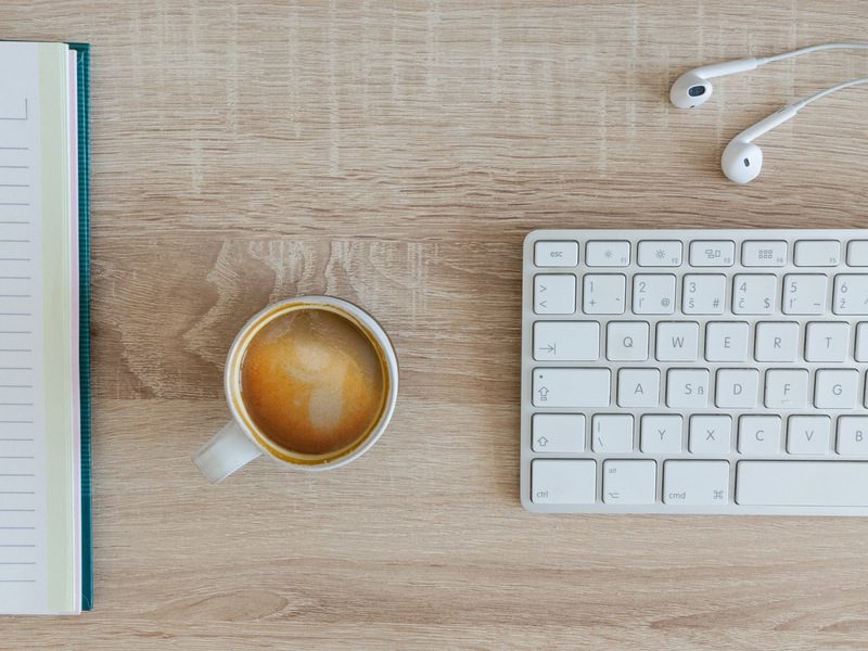 Coffee on table next to keyboard and headphones