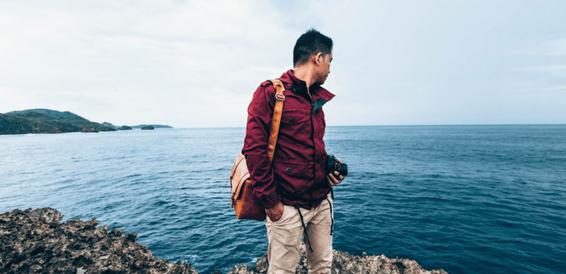 Man standing on rocks looking out at ocean