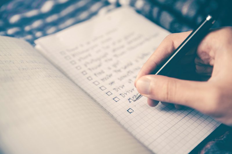 hand holding pen making list in notebook