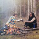 one person pouring drink for friend while camping