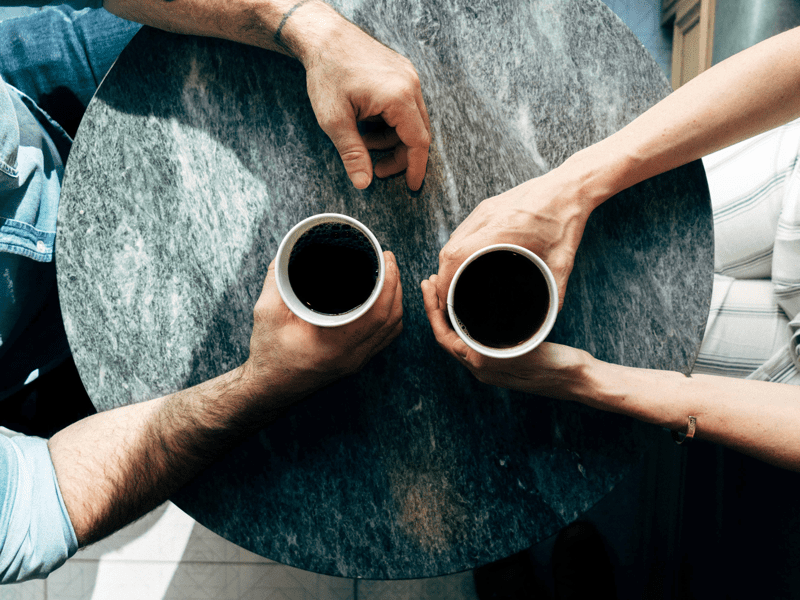 Two people at a table holding cups