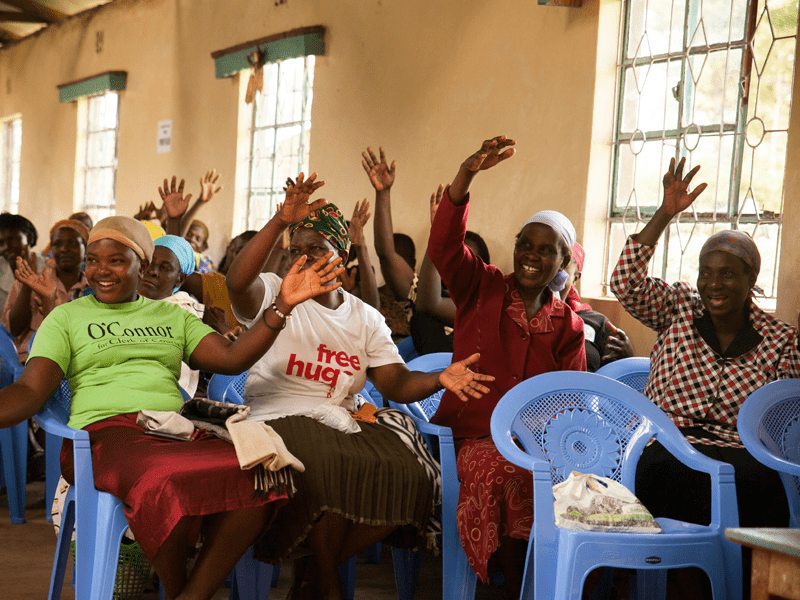 Kenyan women smiling with hands raised