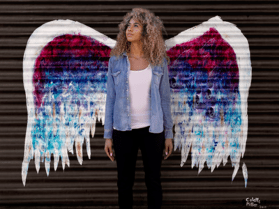 Angel wings painted on wall with woman posing 