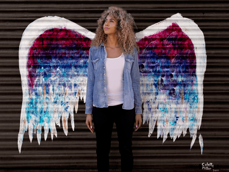 Angel wings painted on wall with woman posing