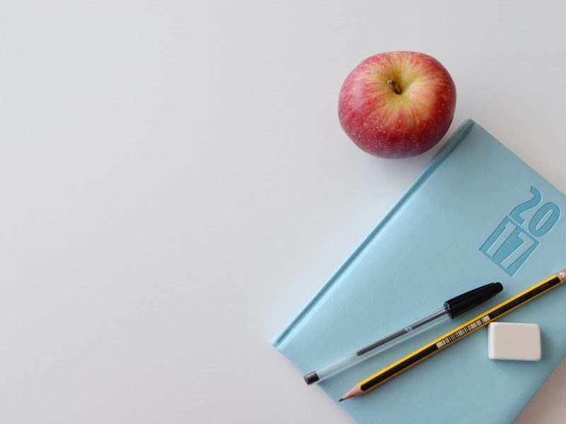 apple next to notebook and pen