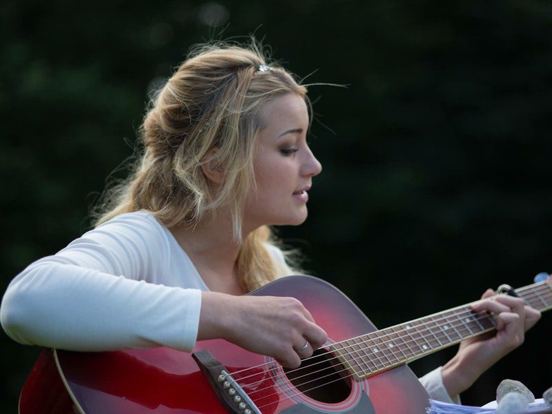 woman playing a red guitar