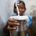 girl holding cup being filled with water