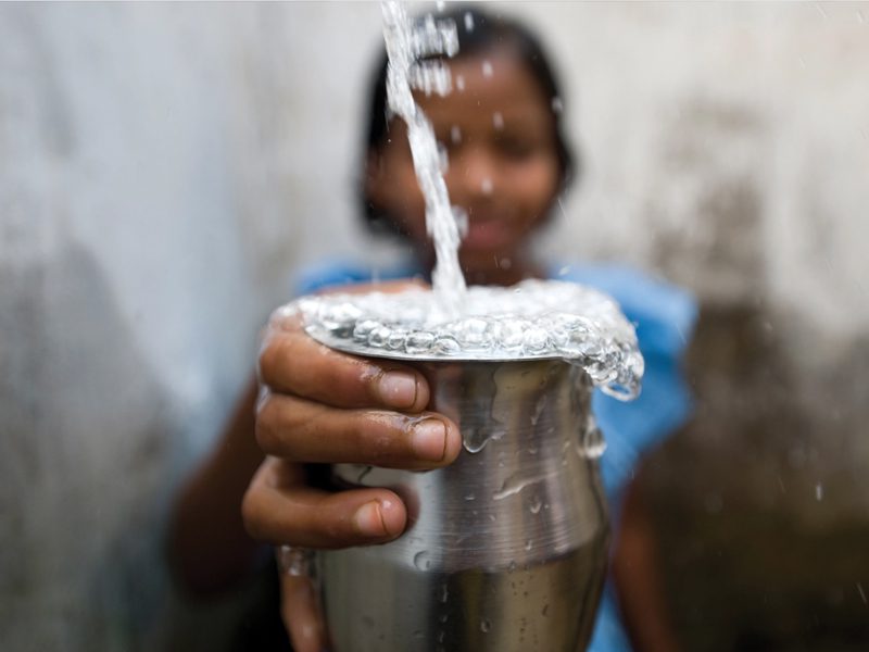 girl holding cup being filled with water