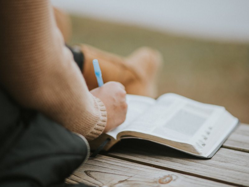 person with pen and Bible