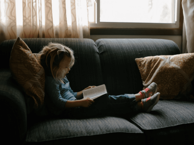 young girl reading on couch