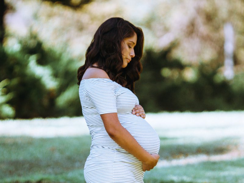 Pregnant woman with arms around stomach