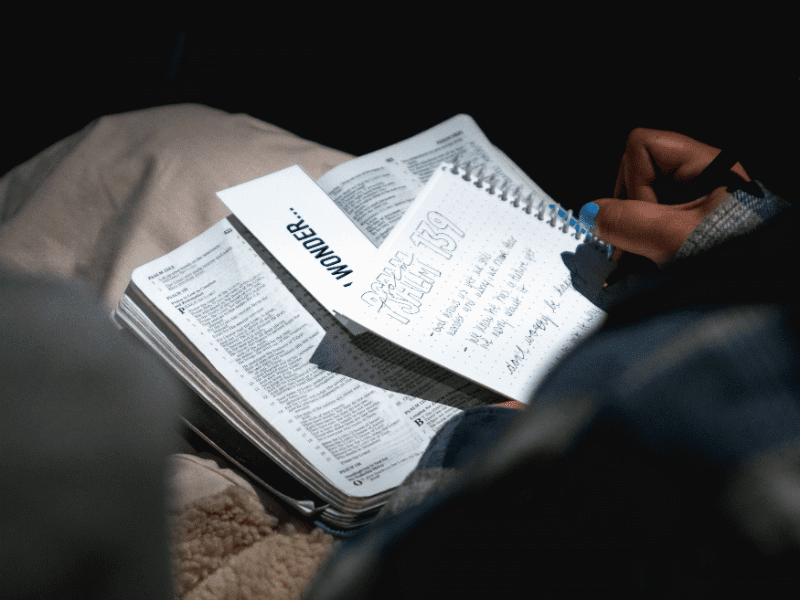 person with Bible and notes on lap