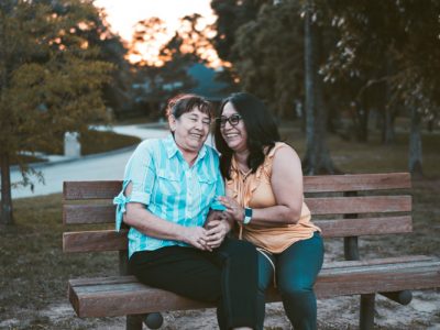 two women sitting on a bench smiling
