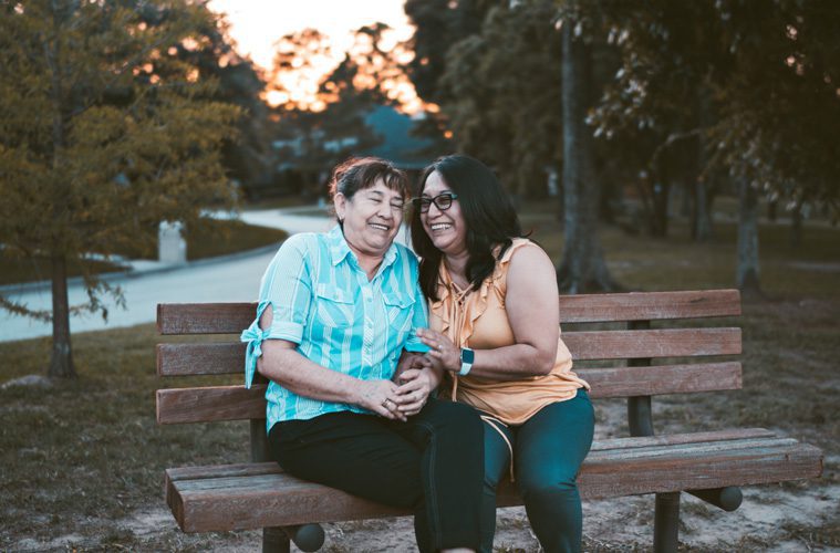 two women sitting on a bench smiling