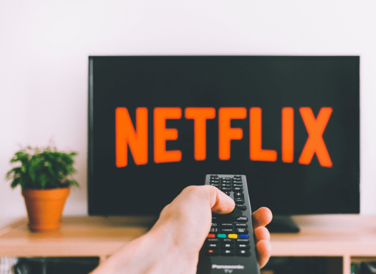 TV remote being pointed at TV with Netflix logo on the screen