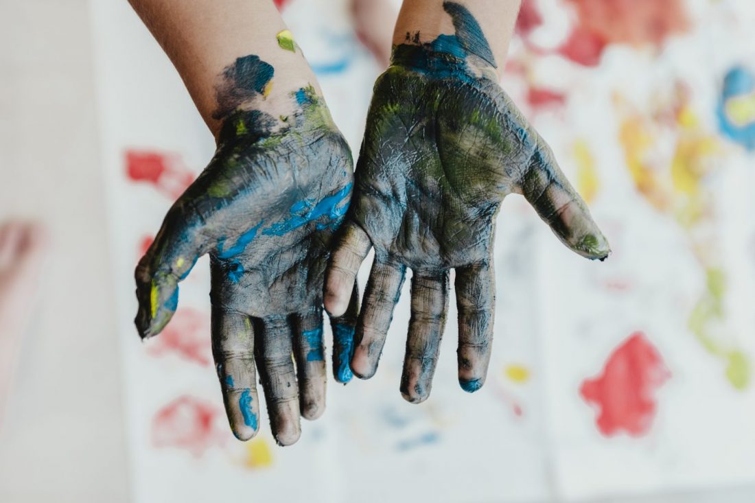 hands with palms up covered in paint